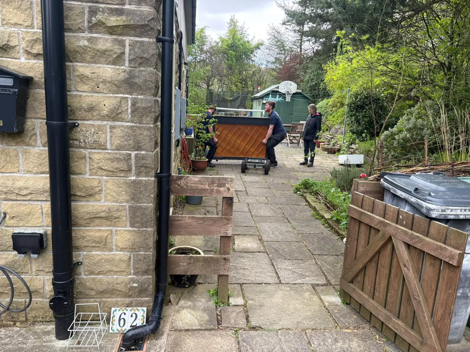 On The Move Removals team carrying a piano through a stone passageway during a removal job in Marsden