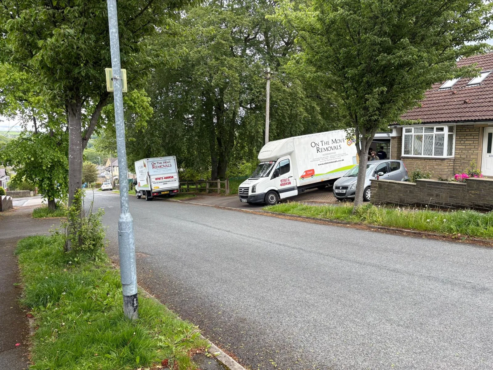 On The Move Removals vans on a leafy road during a house move in Waterloo, Huddersfield