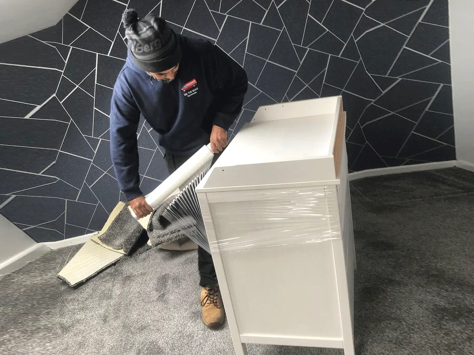 On The Move Removals crew shrink-wrapping a piece of furniture before lifting it into the van in Huddersfield